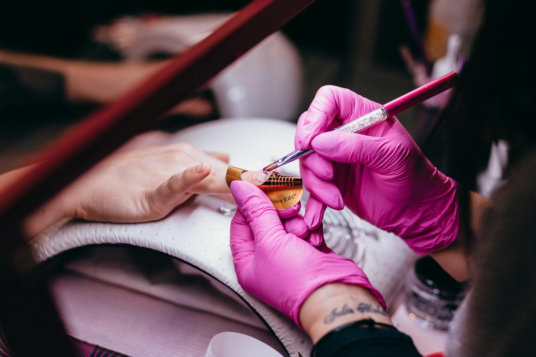 Clear acrylic monomer in a dappen dish and pink acrylic powder ready for an acrylic nail application