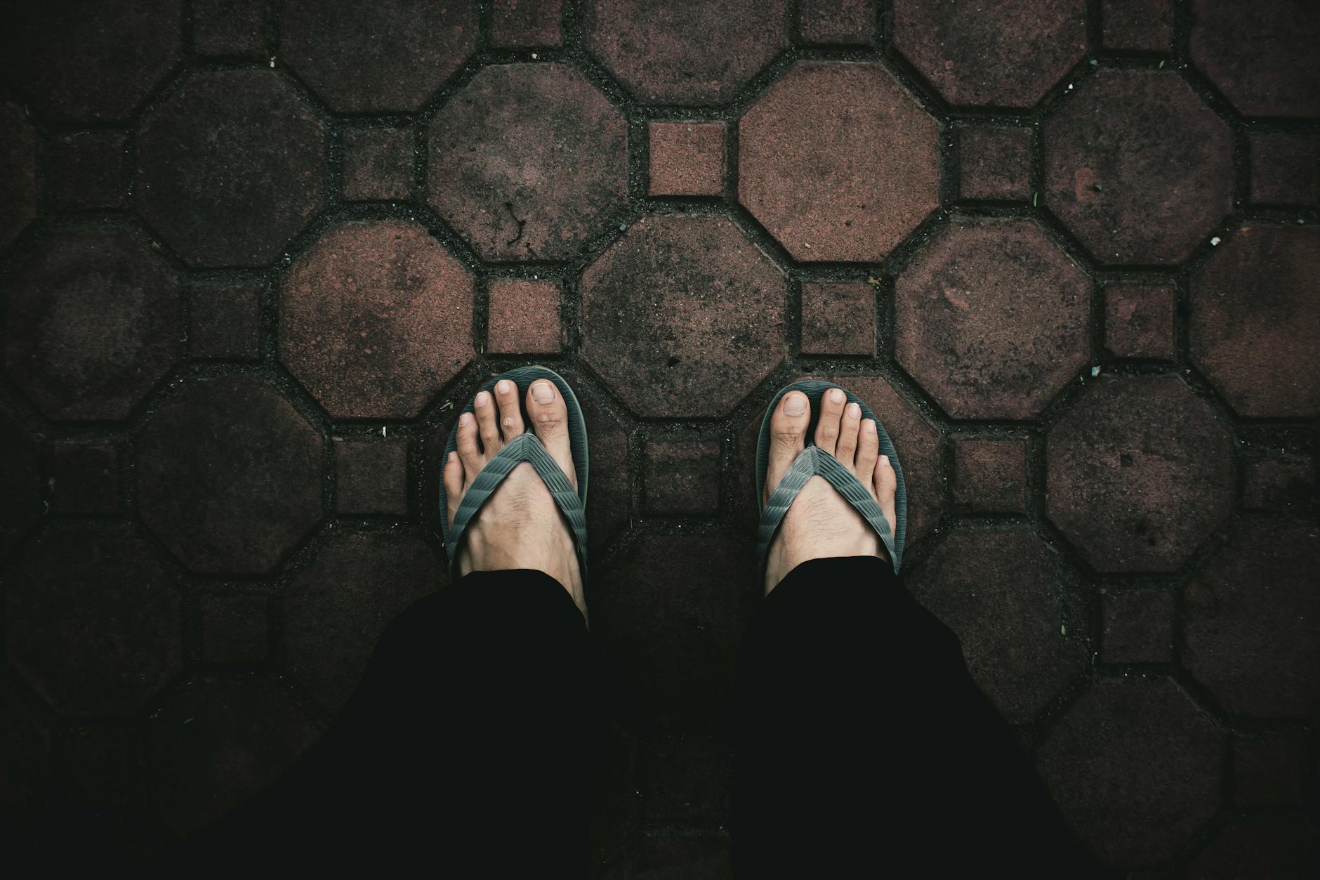 Bare feet in strapped sandals on a hot sidewalk illustrating summer pedicure durability